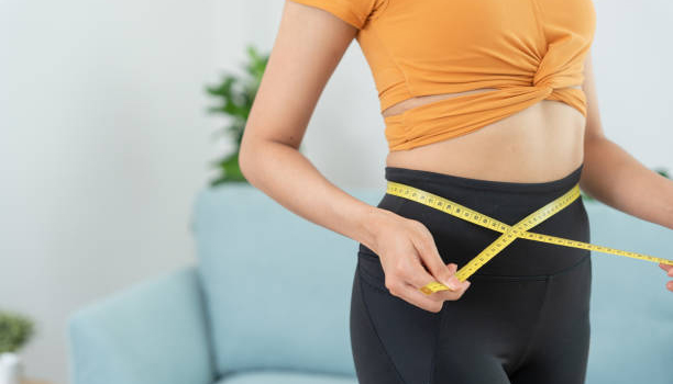 Diet and dieting. Beauty slim female body use tape measure. Woman in exercise clothes achieves weight loss goal for healthy life, crazy about thinness, thin waist, nutritionist.