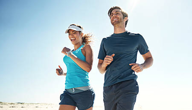 Shot of a young couple running along the beach together